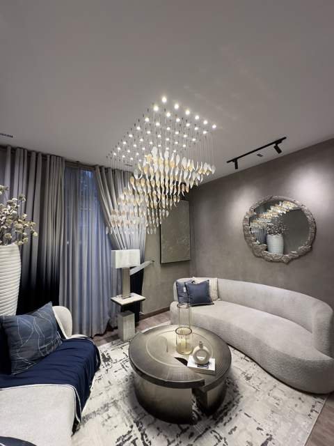 Sitting room with layered chandelier and round mirror